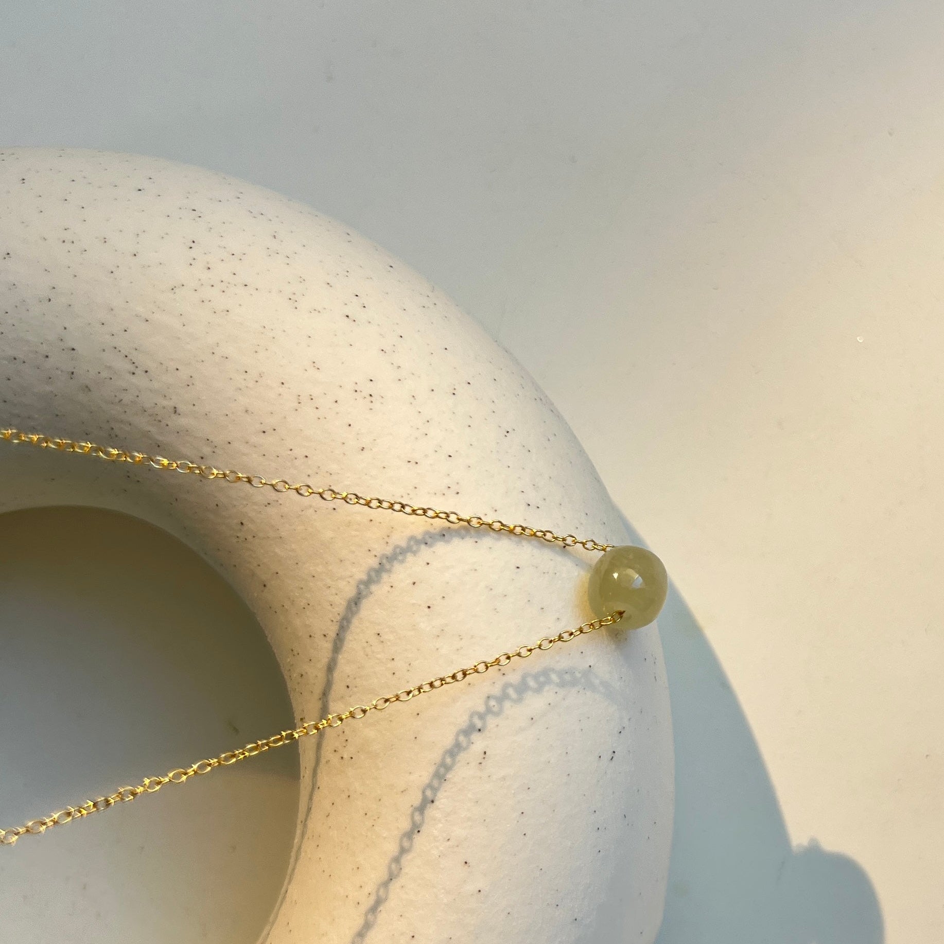 Necklace with a green bead on a textured stone surface